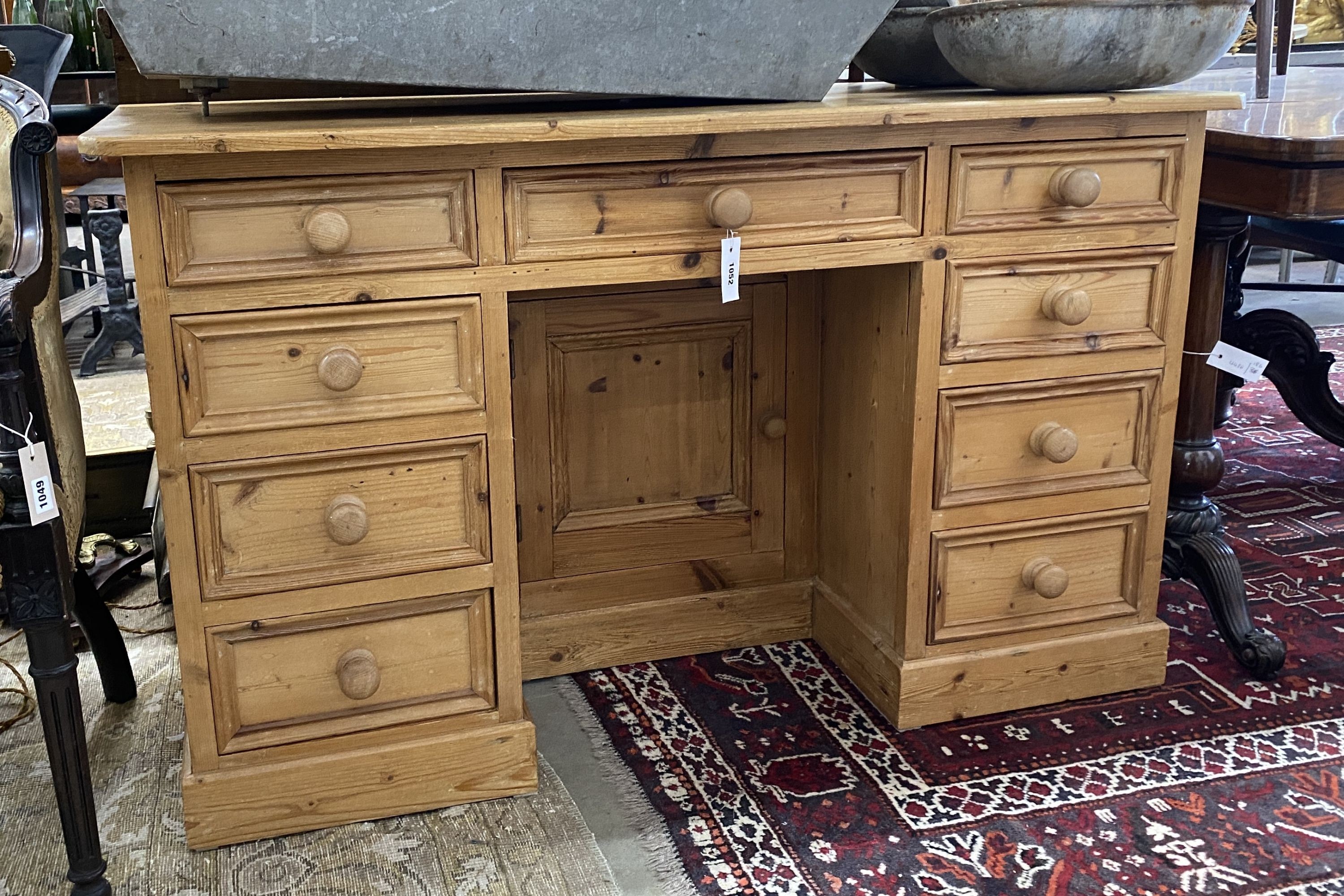 A Victorian style pine kneehole nine drawer desk with recessed cupboard, length 130cm, depth 50cm, height 79cm